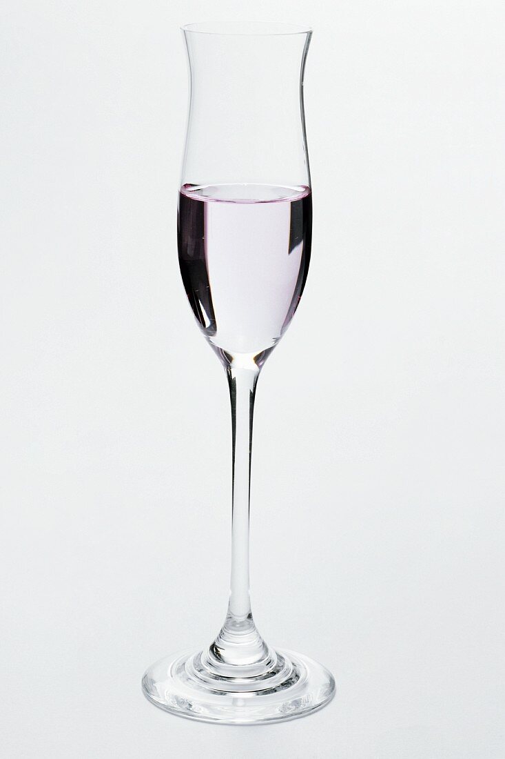 Ein halb gefülltes Glas mit rosa Grappa