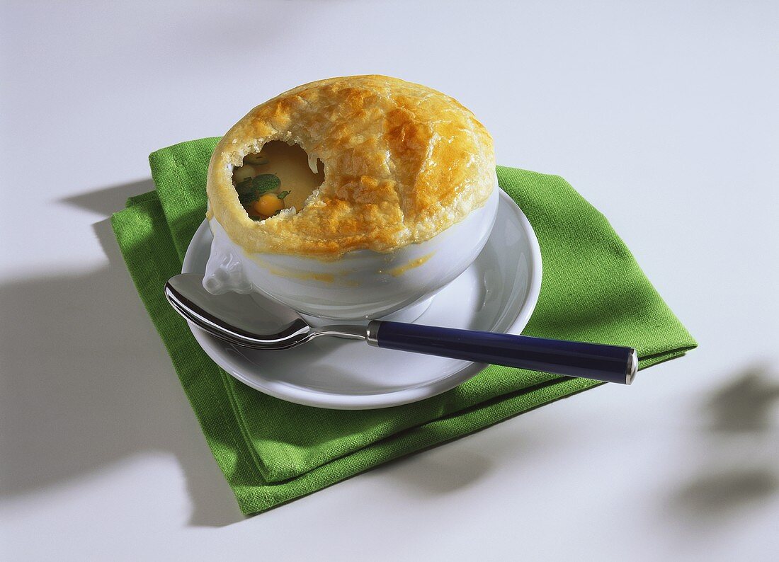 Clear vegetable broth with puff pastry topping in soup bowl