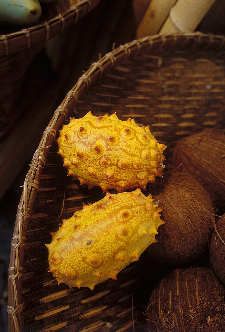 Two kiwanos (horned melons) with coconuts in a basket