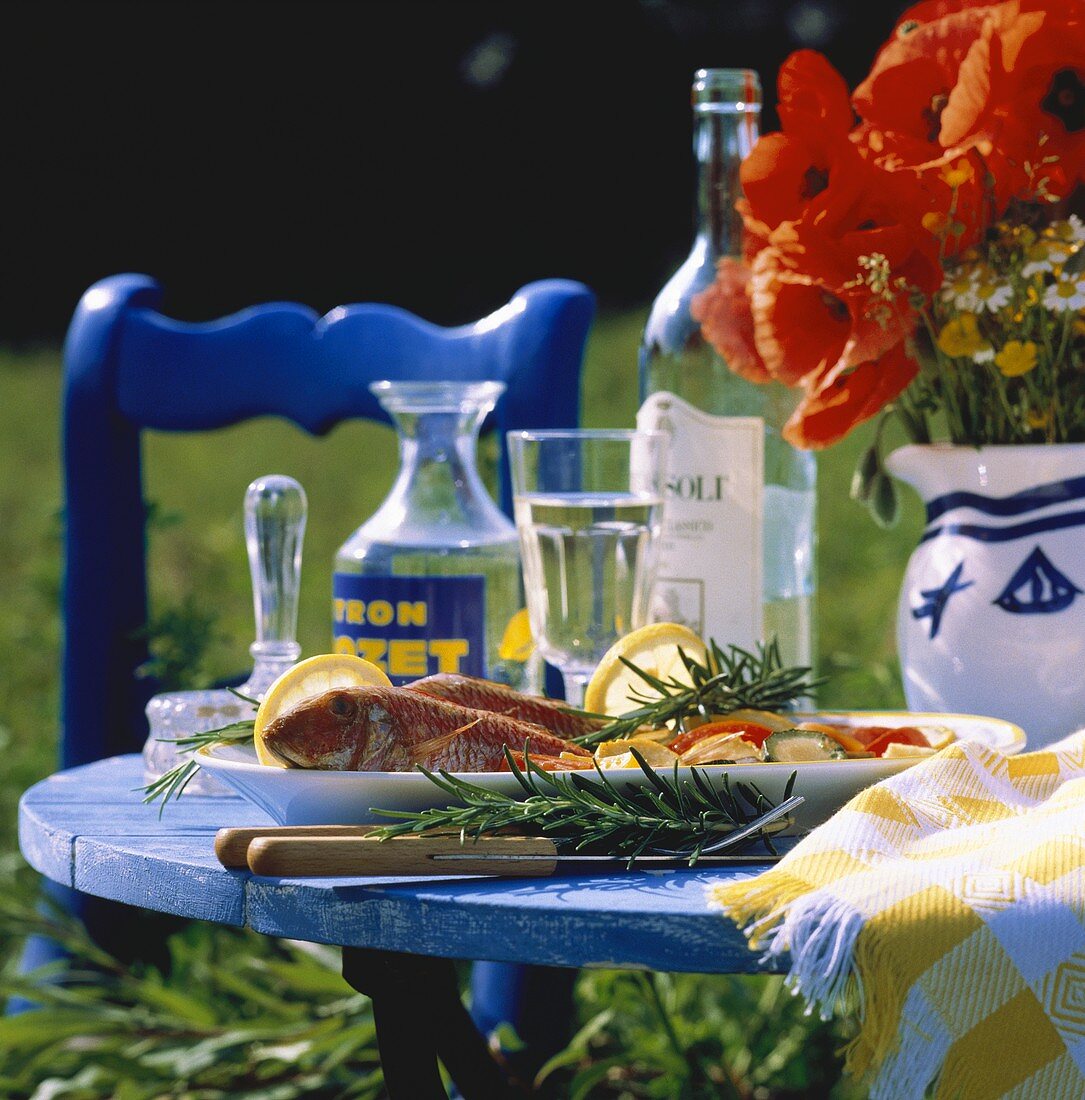 Red mullet with vegetables on table in open air with poppies