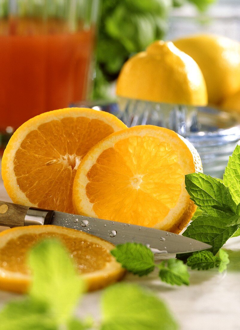 Orange, teilweise in Scheiben geschnitten, mit Messer, Minze