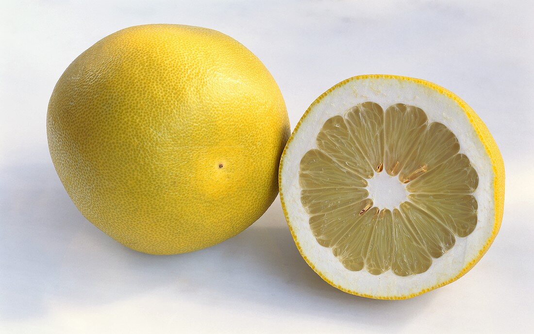 Pomelo, whole and halved, on light background