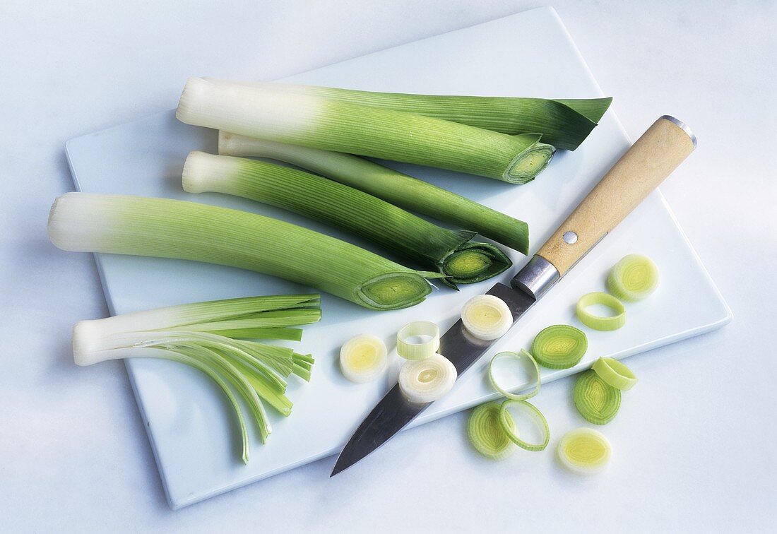 Leek stalks and rings with knife on chopping board