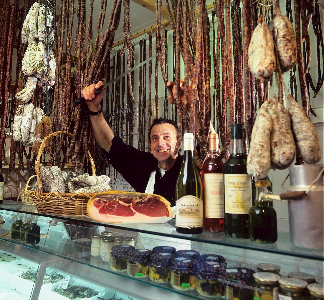 Butcher with sausages & deli-goods in the shop (Provence)