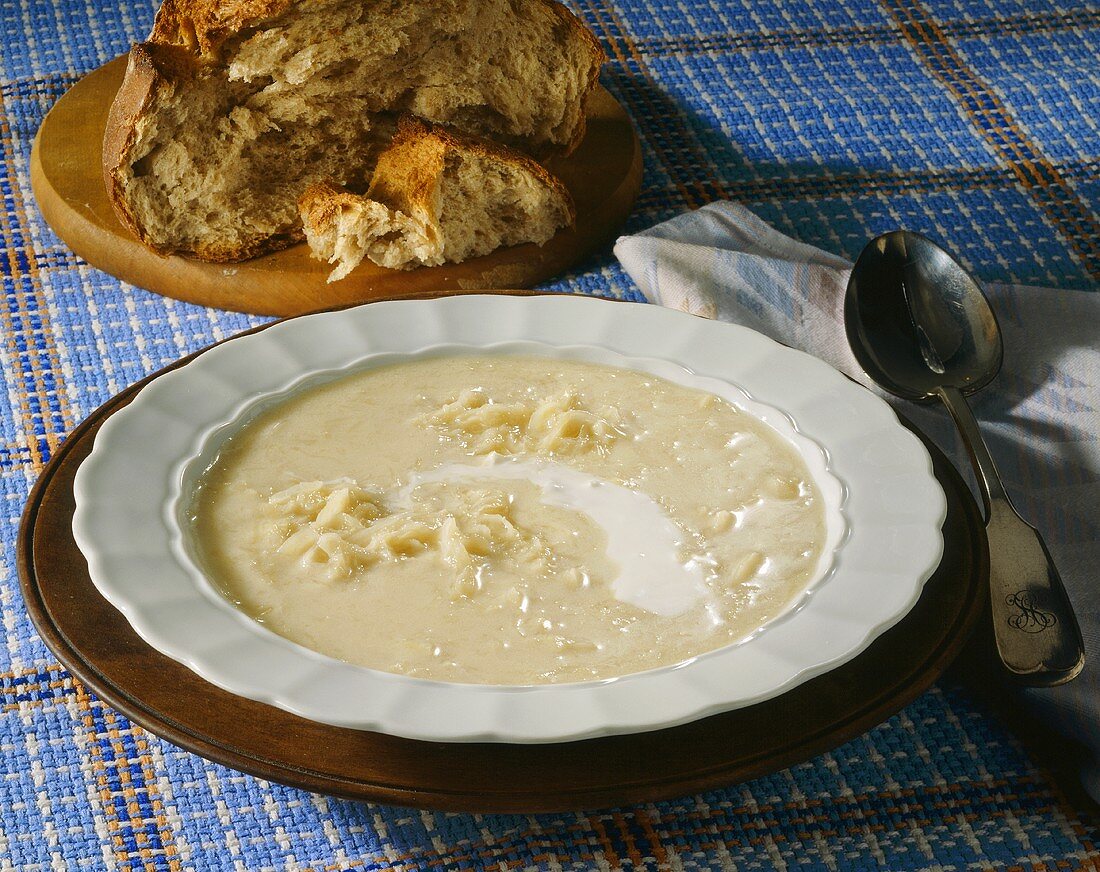 Sauerkrautsuppe mit saurer Sahne; Landbrot auf Holzteller