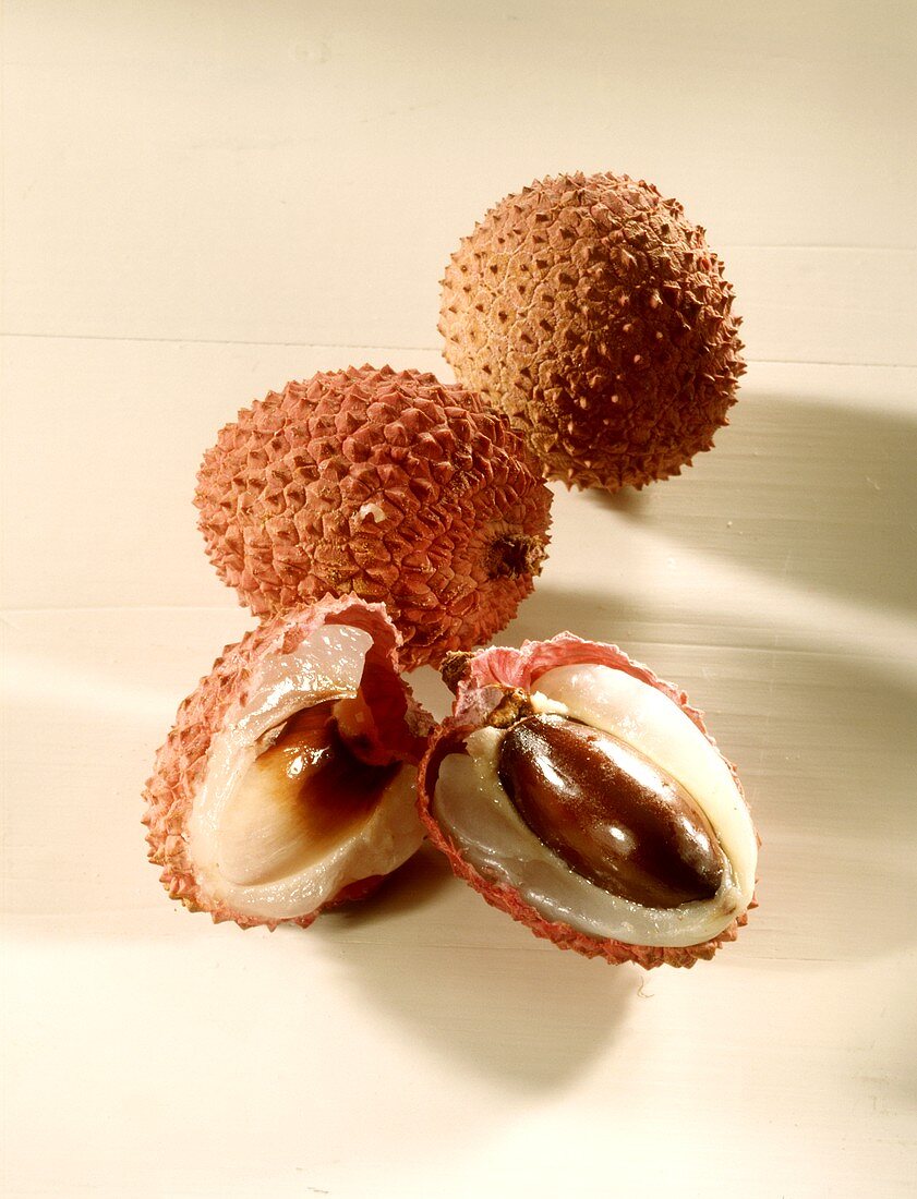 Halved lychee with stone in front of two lychees