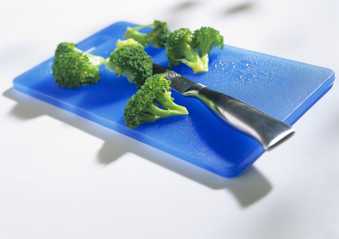 Broccoli florets on blue chopping board with knife