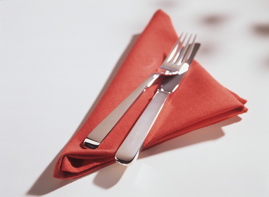 Besteck (Messer, Gabel) auf roter Stoffserviette