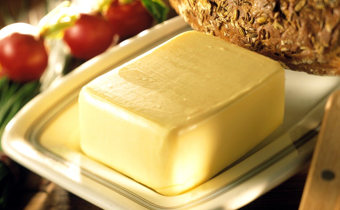 Butter auf Butterdose, dahinter Brot und Radieschen