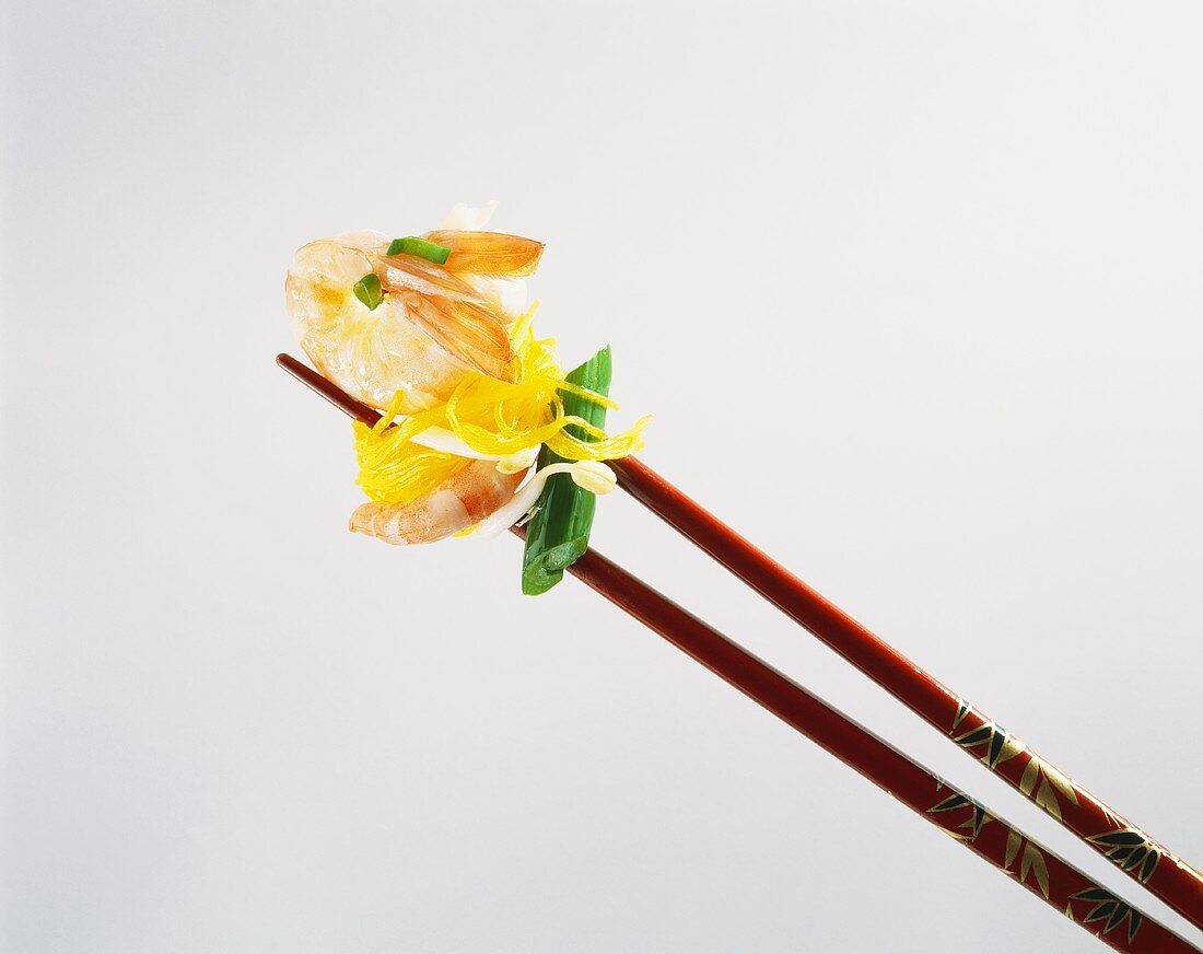 Shrimp with glass noodles between red chopsticks