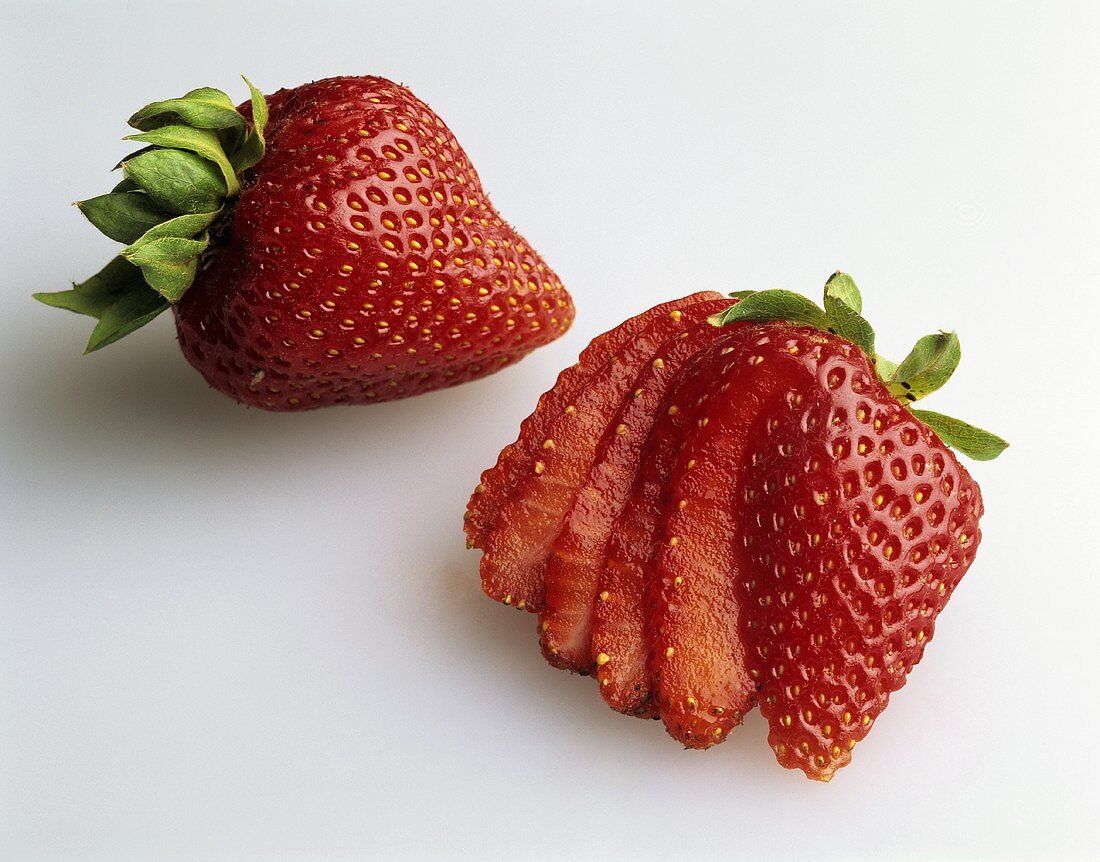 Zwei Erdbeeren, eine davon in Scheiben geschnitten