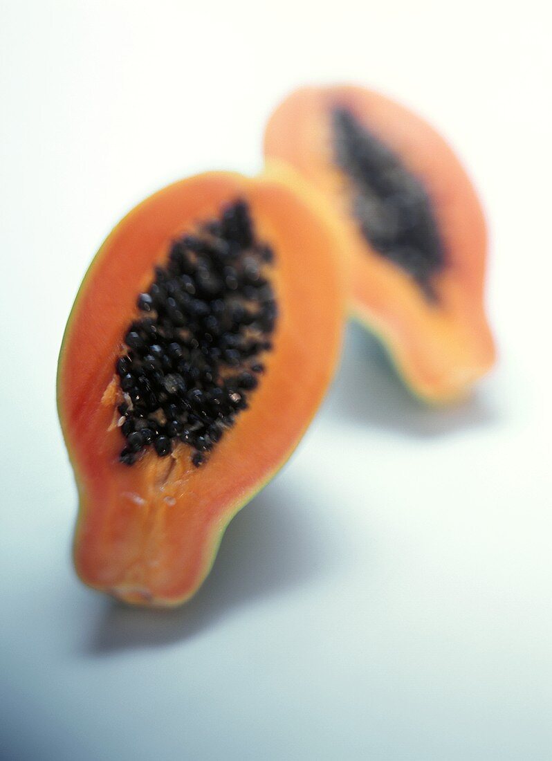 Two papaya halves on a pale blue background