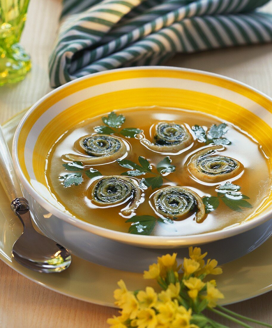 Vegetable broth with herb spirals and parsley leaves