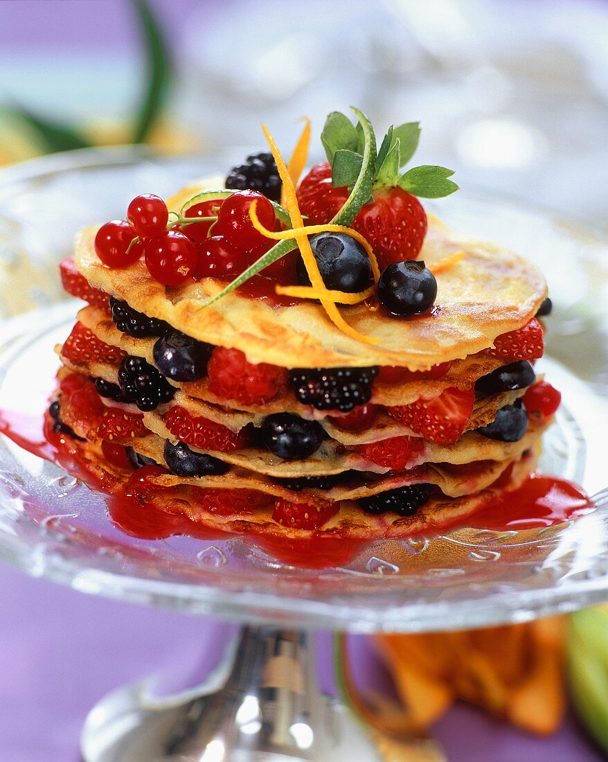 Layered pancakes with berries on glass plate