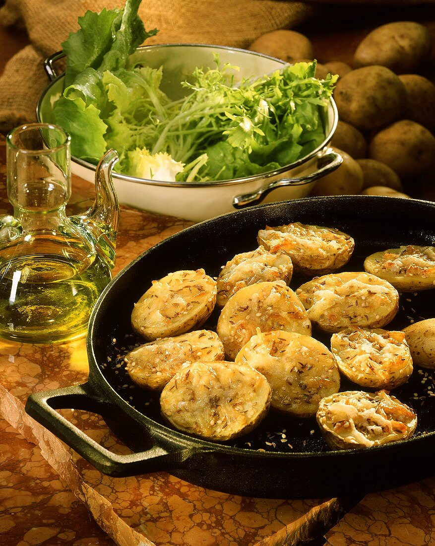 Ofenkartoffeln mit Käse, Kümmel und Sesam in Pfanne; Salat