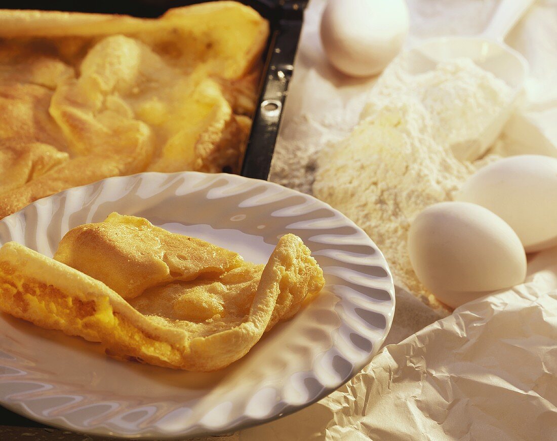 Pfannkuchentorte auf Teller und Backblech; Deko: Eier, Mehl