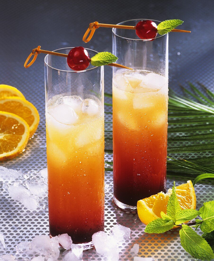 Tequila sunrise with ice cubes in two tall glasses
