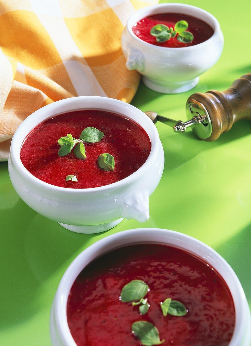 Rote-Bete-Suppe mit Basilikumblättchen in Suppentassen