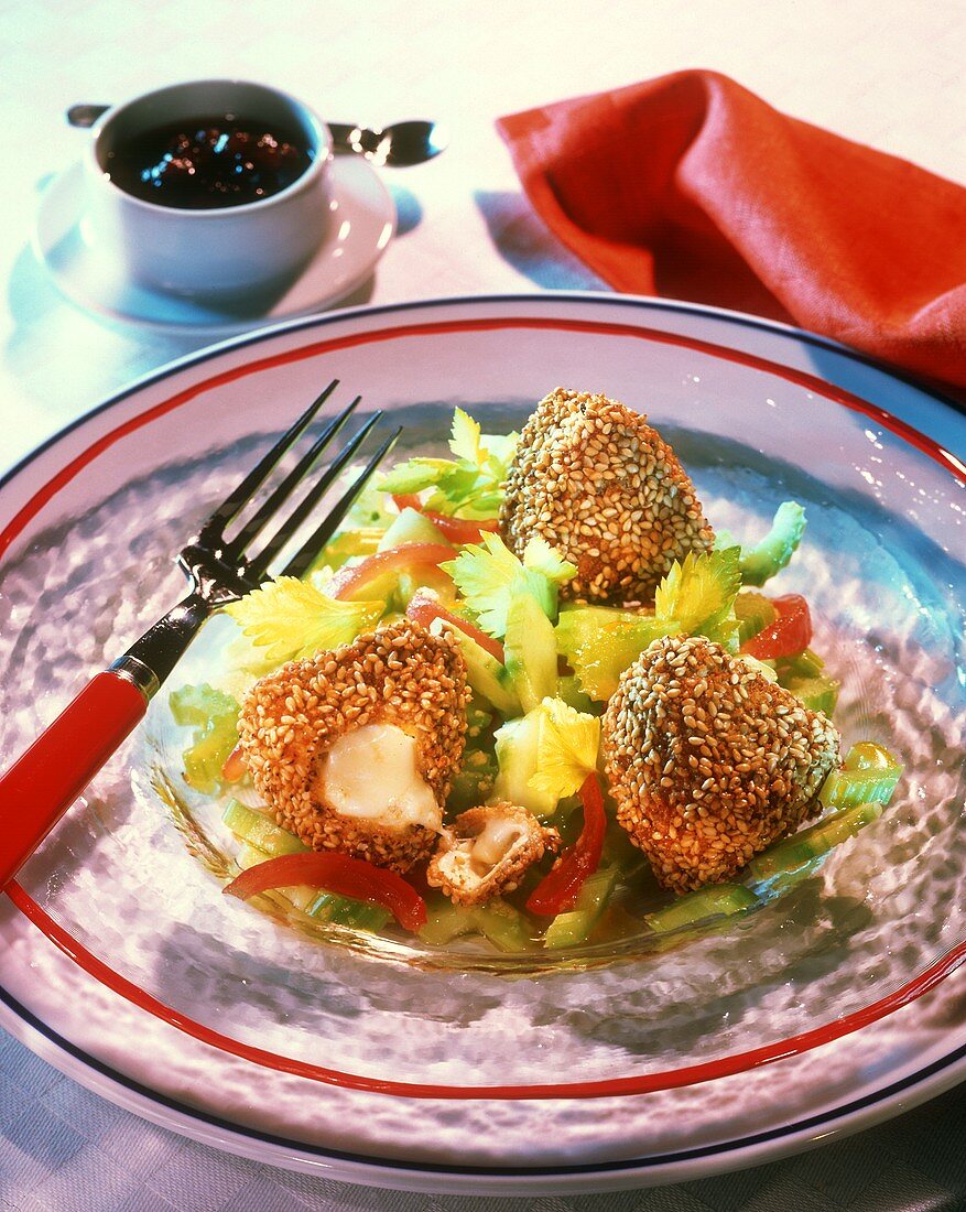 Deep-fried cheese balls with sesame crust on vegetable salad