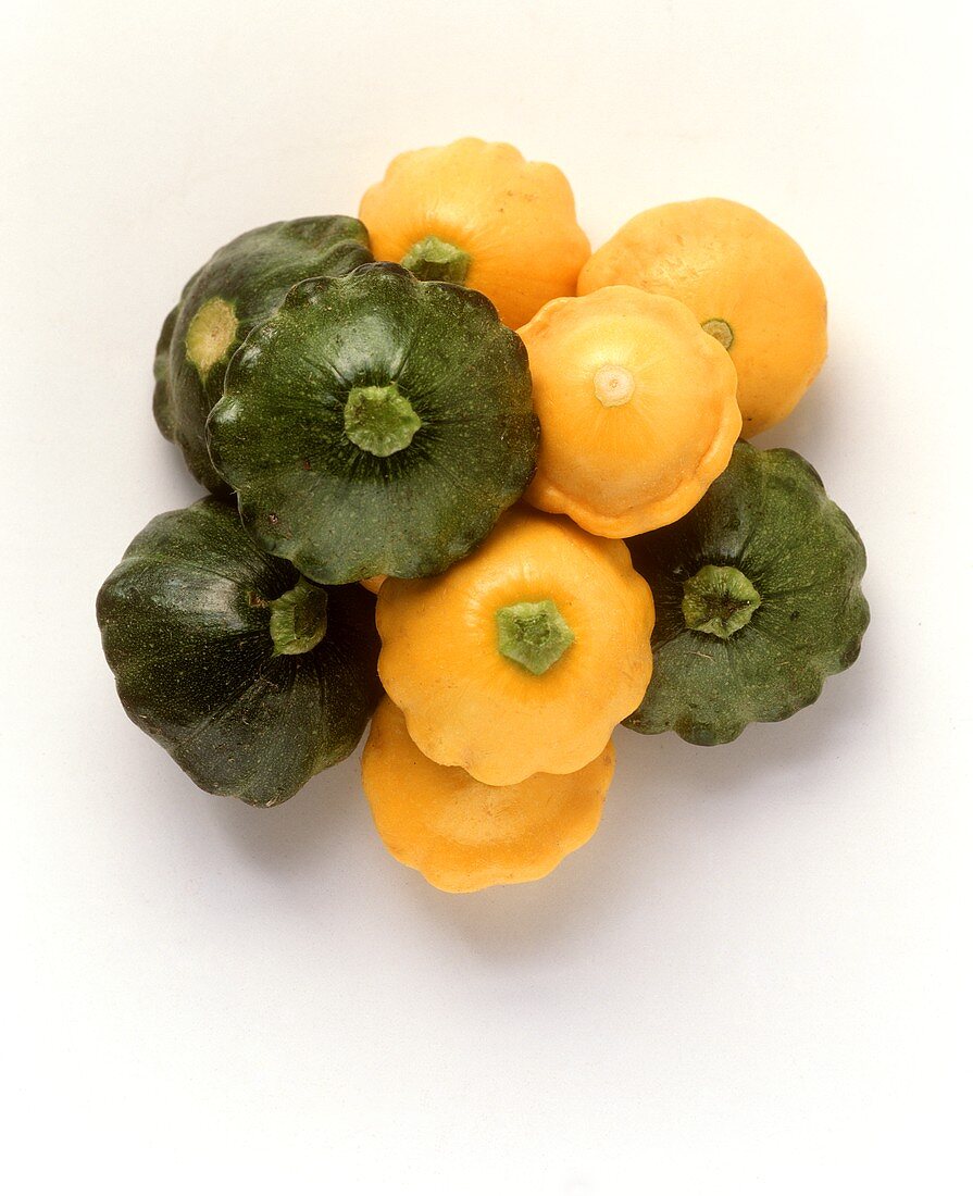 Yellow and green mini-patty pan squashes on white background