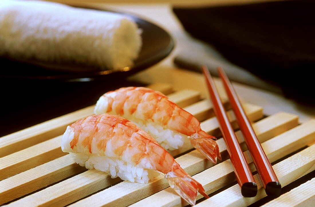Garnelen-Sushi (Ebi) auf Holzgitter mit roten Stäbchen