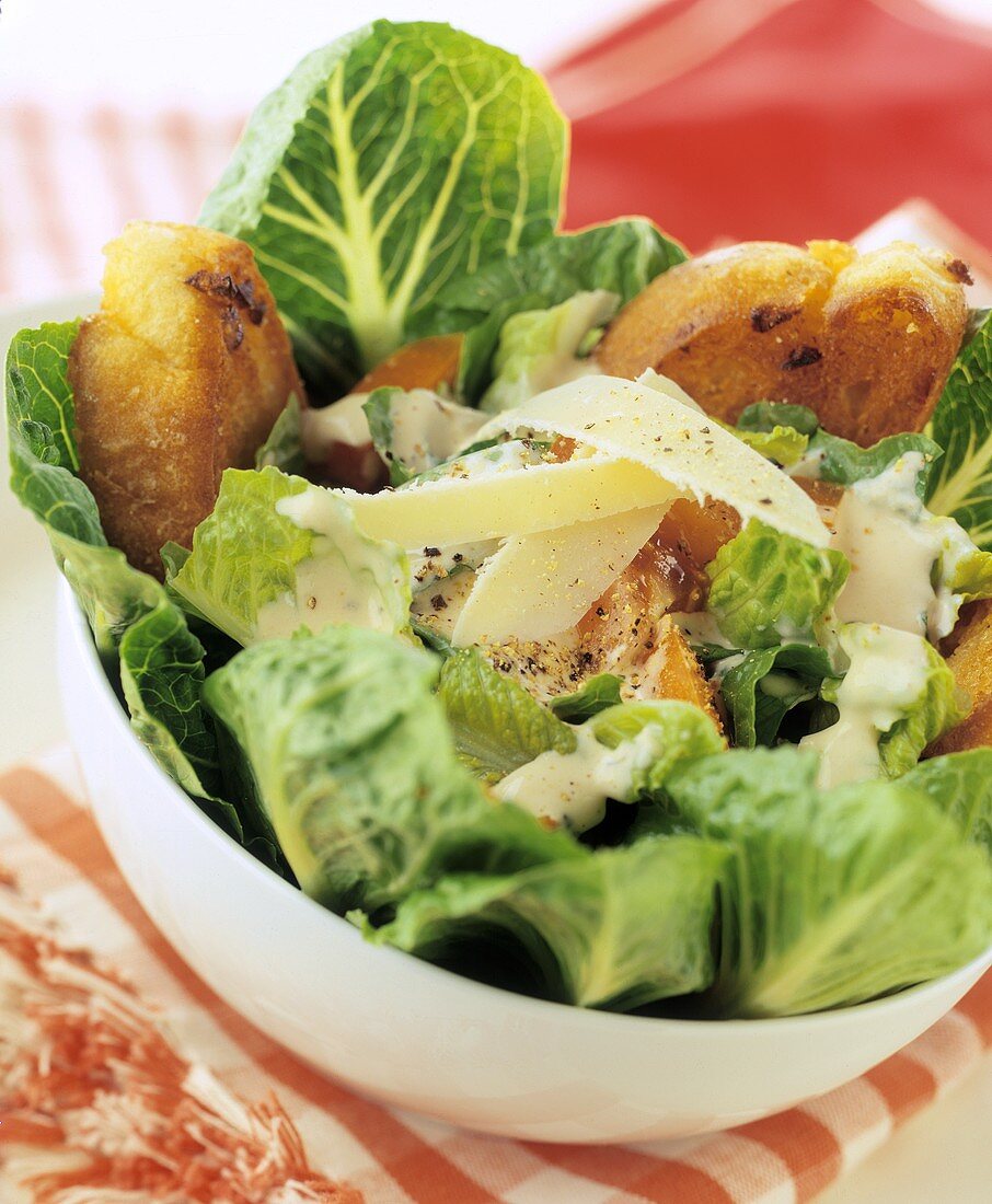 Cäsarsalat mit Parmesanspänen und Weißbrot in Schüssel