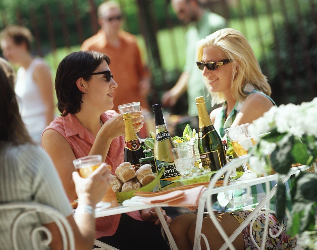 Women at a table in open air with drinks and pastries