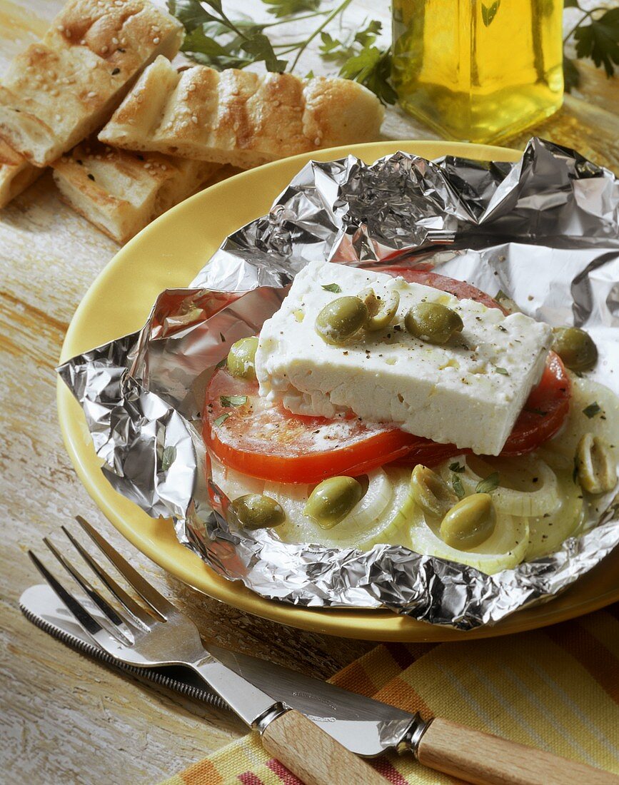 Grilled sheep's cheese in foil with tomato, onion, olive