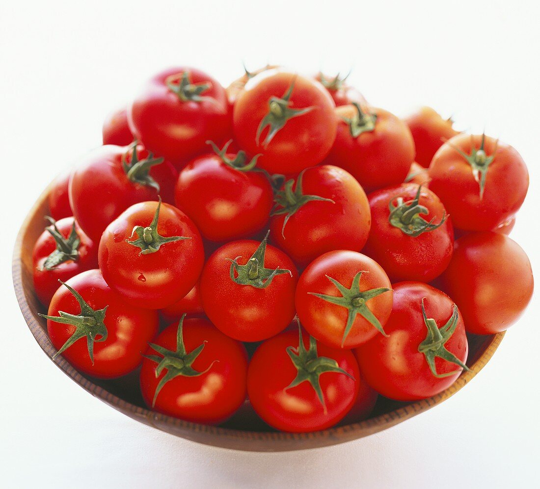 Viele Tomaten in einer braunen Schale auf weißem Untergrund