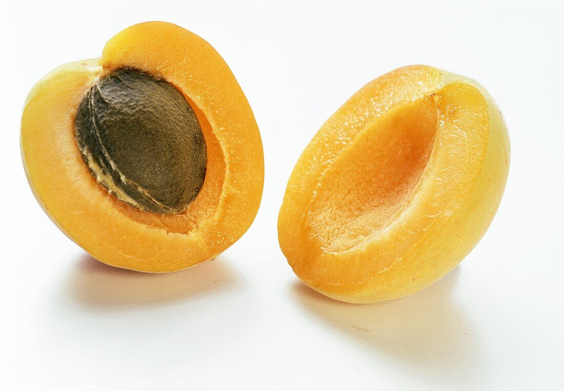 Zwei Aprikosenhälften, eine davon mit Kern