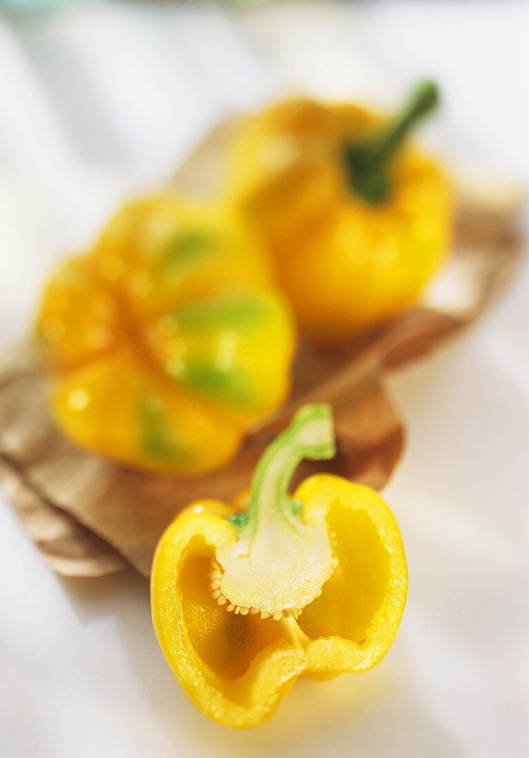 Gelbe Paprikahälfte vor gelben Paprika auf braunem Papier
