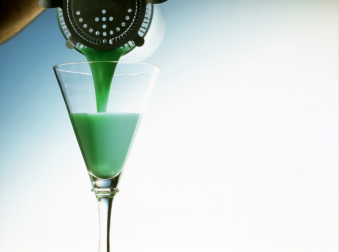 Grasshopper Cocktail mit Minzlikör aus Shaker in Glas gießen