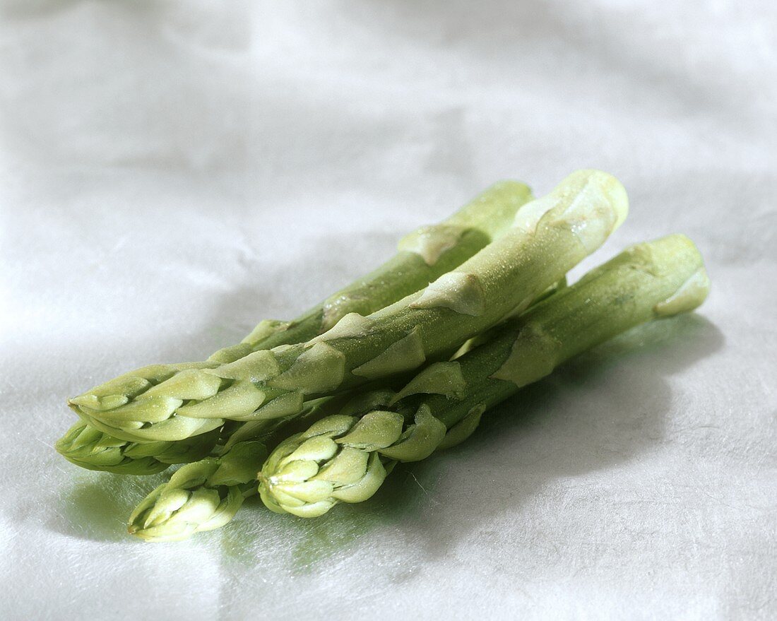 Green asparagus with drops of water on light background