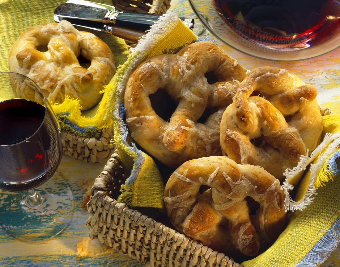 Cheese pretzels in bread basket, one pretzel beside it; wine