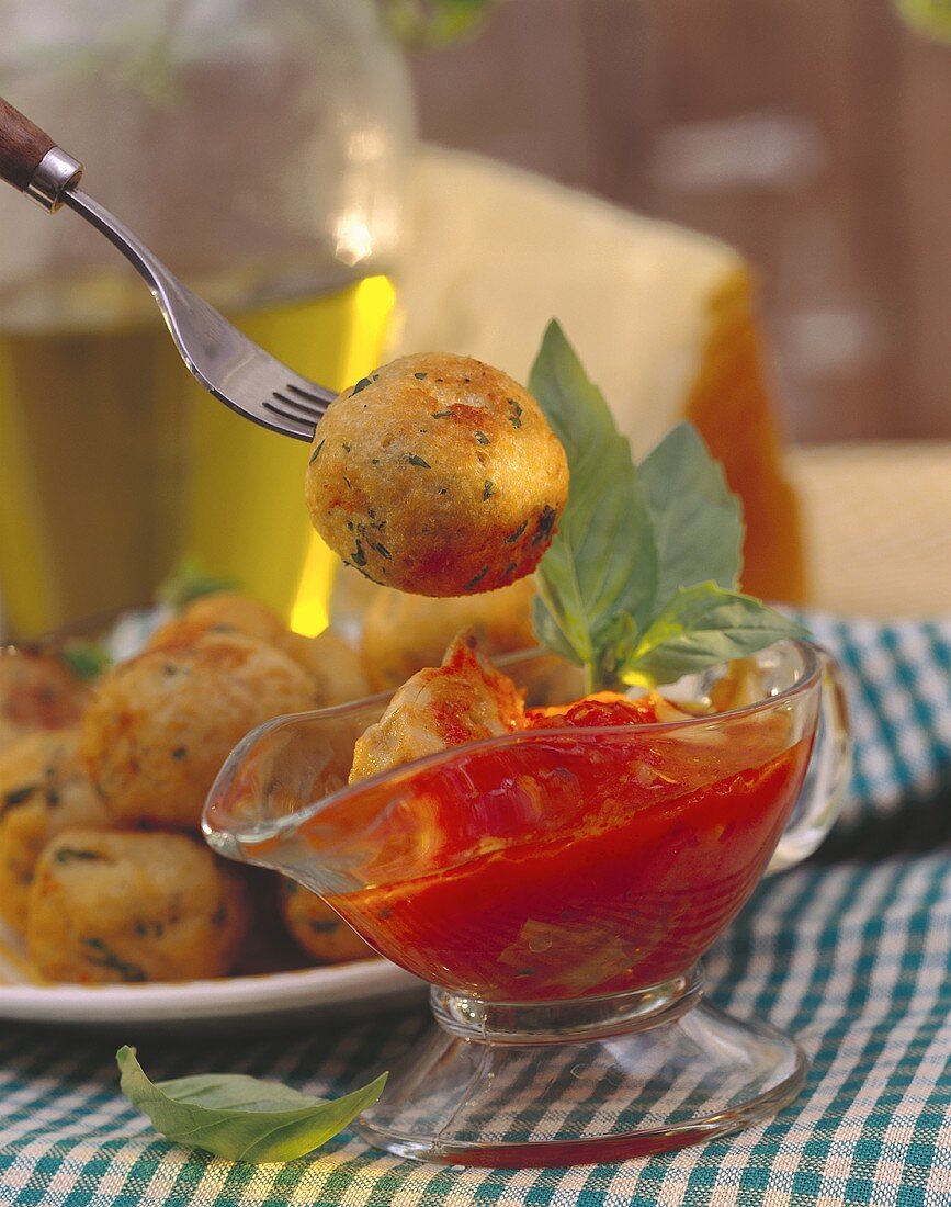 Brotbällchen auf Teller und Gabel über Tomatensauce