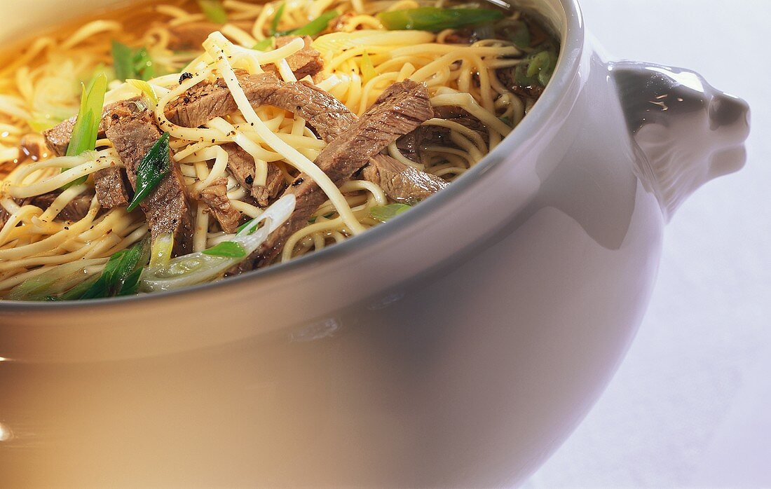 Noodle soup with beef and spring onions in pot