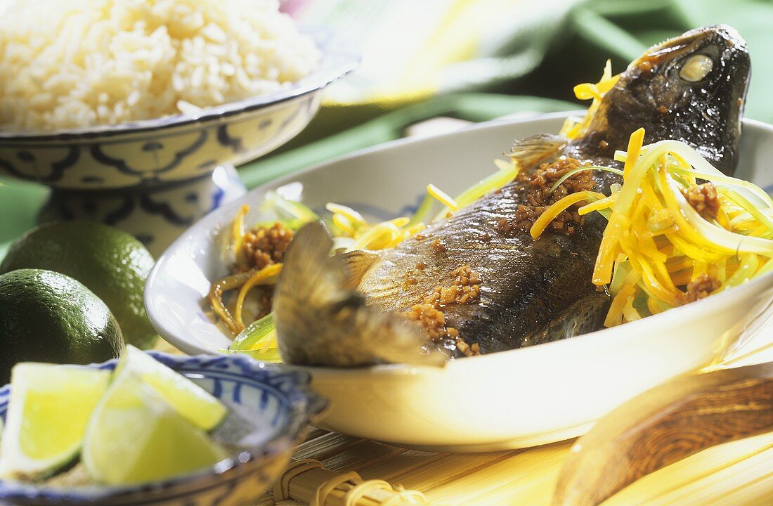 Thai-Forelle in Folie auf Teller, Limetten und Reis