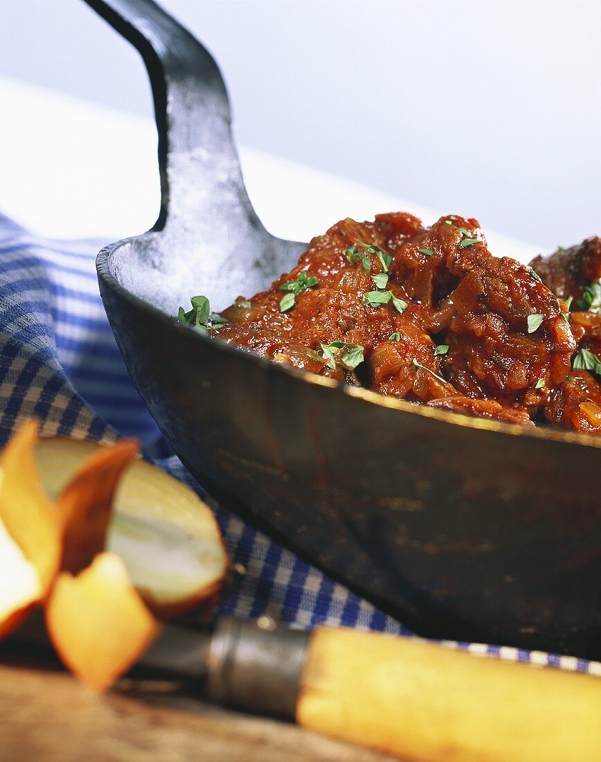 Saftgulasch mit Zwiebeln in einer Gusseisenpfanne