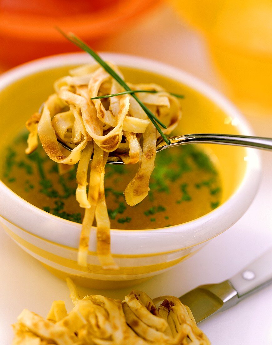 Pancake soup with chives on spoon & in bowl