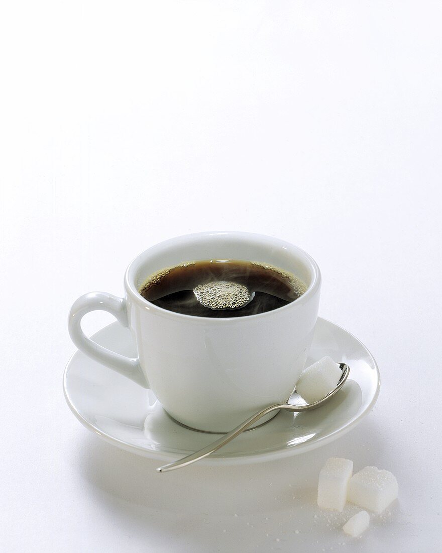 Schwarzer Kaffee in weisser Tasse,Zuckerwürfel auf Löffel