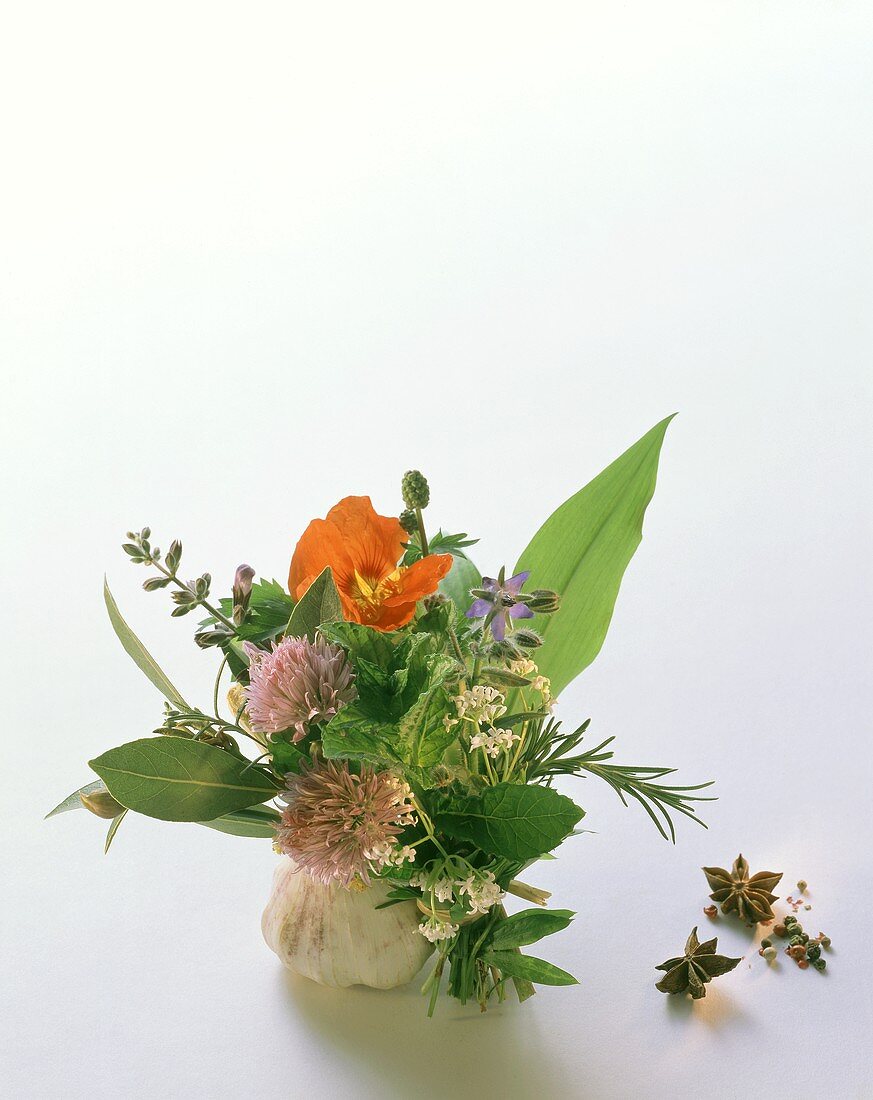 Colourful herb bouquet with watercress flowers beside garlic