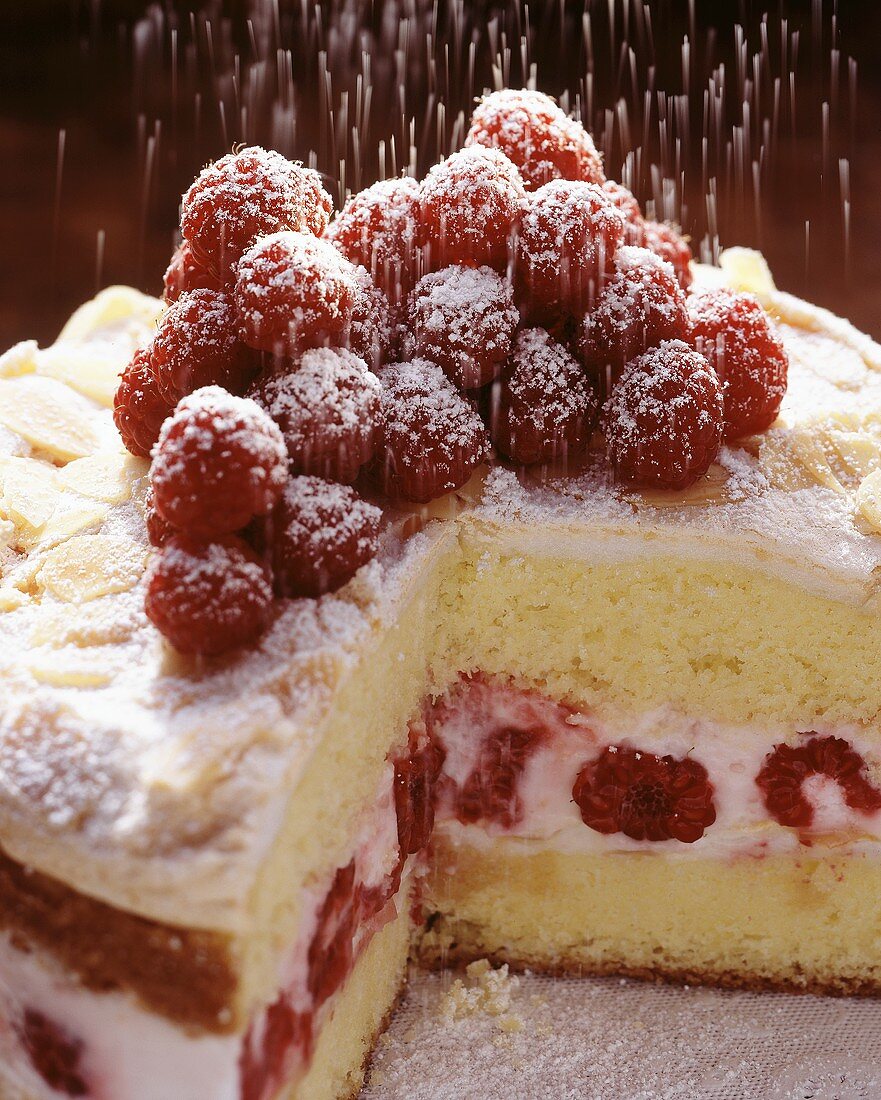 Sprinkling layer cake with raspberries with icing sugar