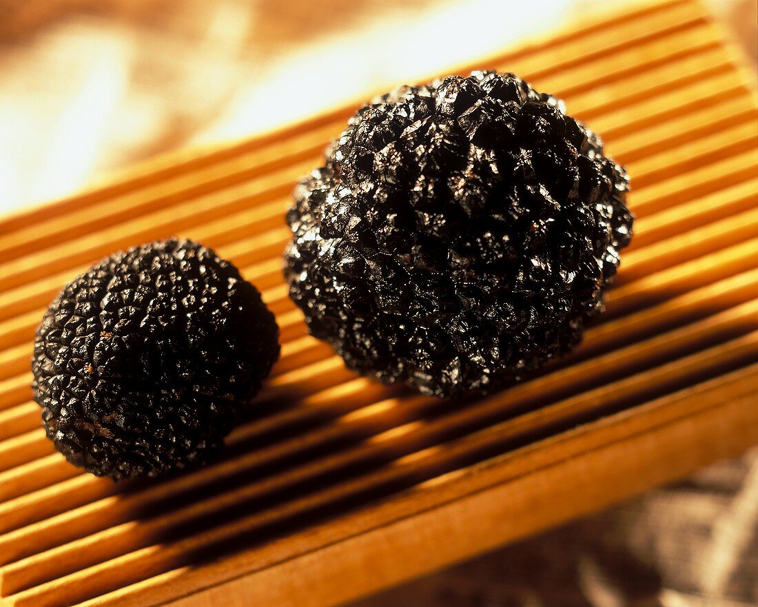 Two black truffles on ribbed wooden board