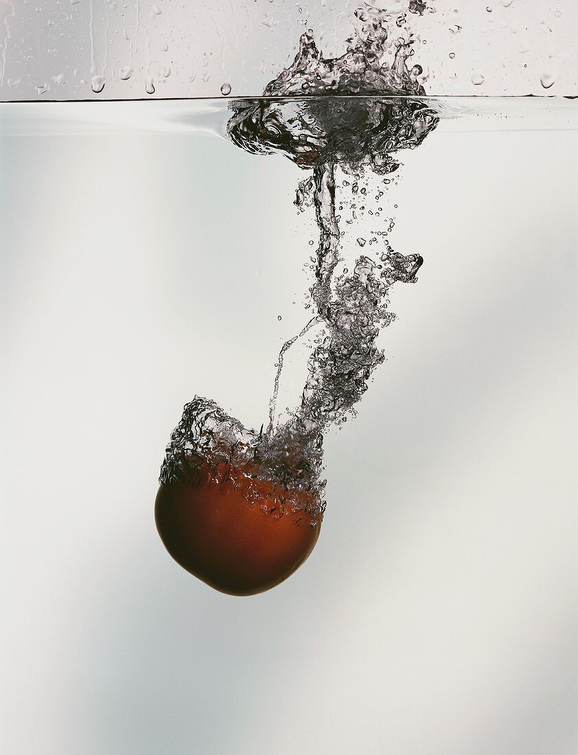Eine Tomate fällt ins Wasser