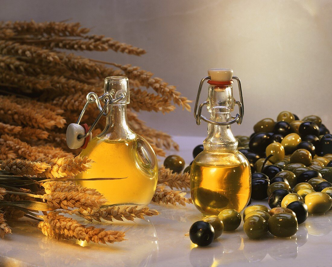 Still life with wheatgerm oil and olive oil; corn, olives