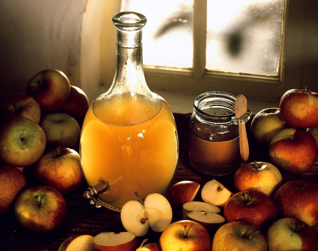 Apfelessig in Flasche, ein Glas Honig und frische Äpfel