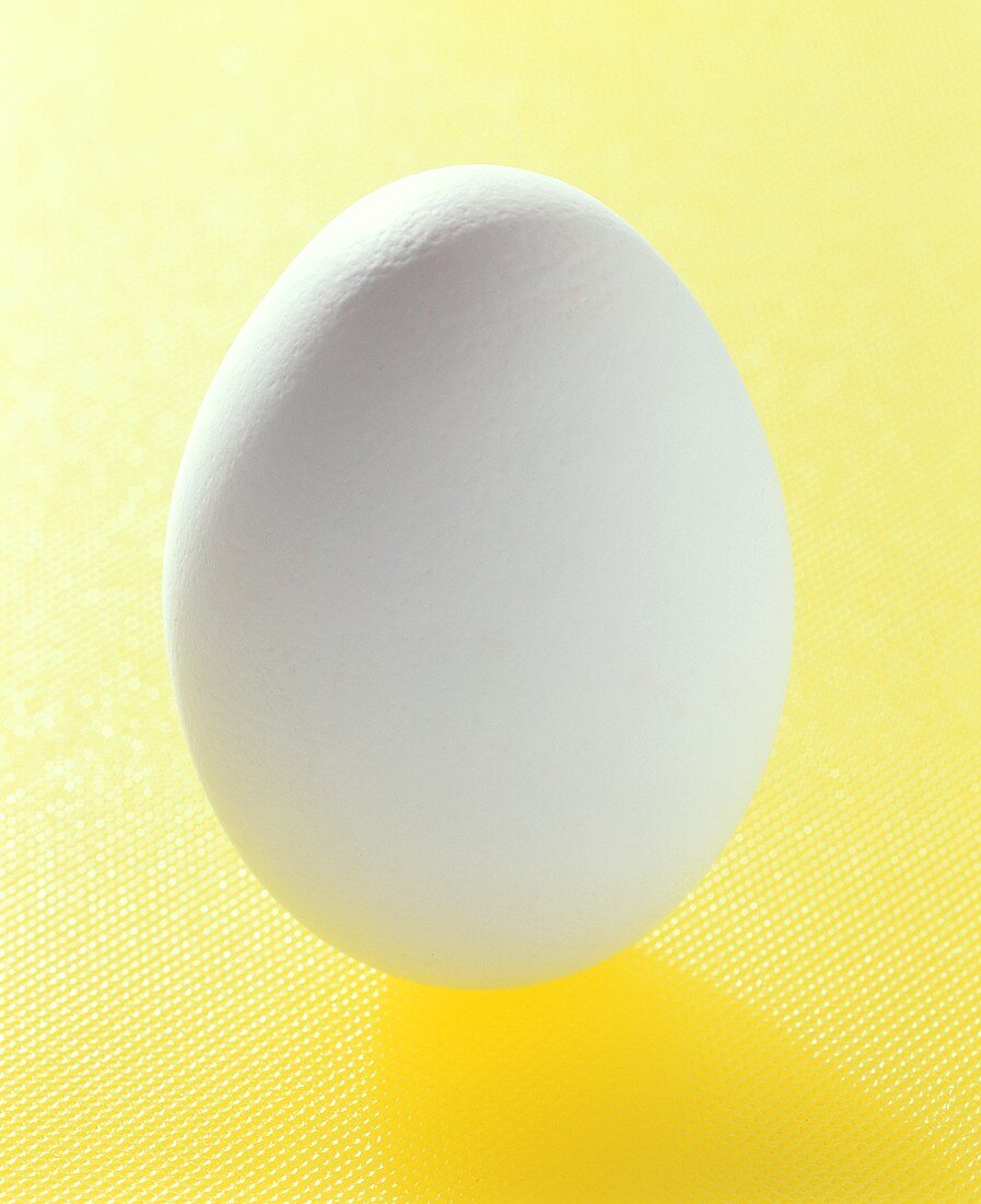 Ein weisses Ei auf gelbem Untergrund