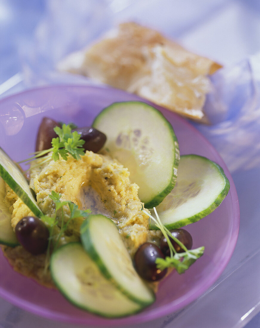 Chick pea puree with cucumber slices and olives on plate