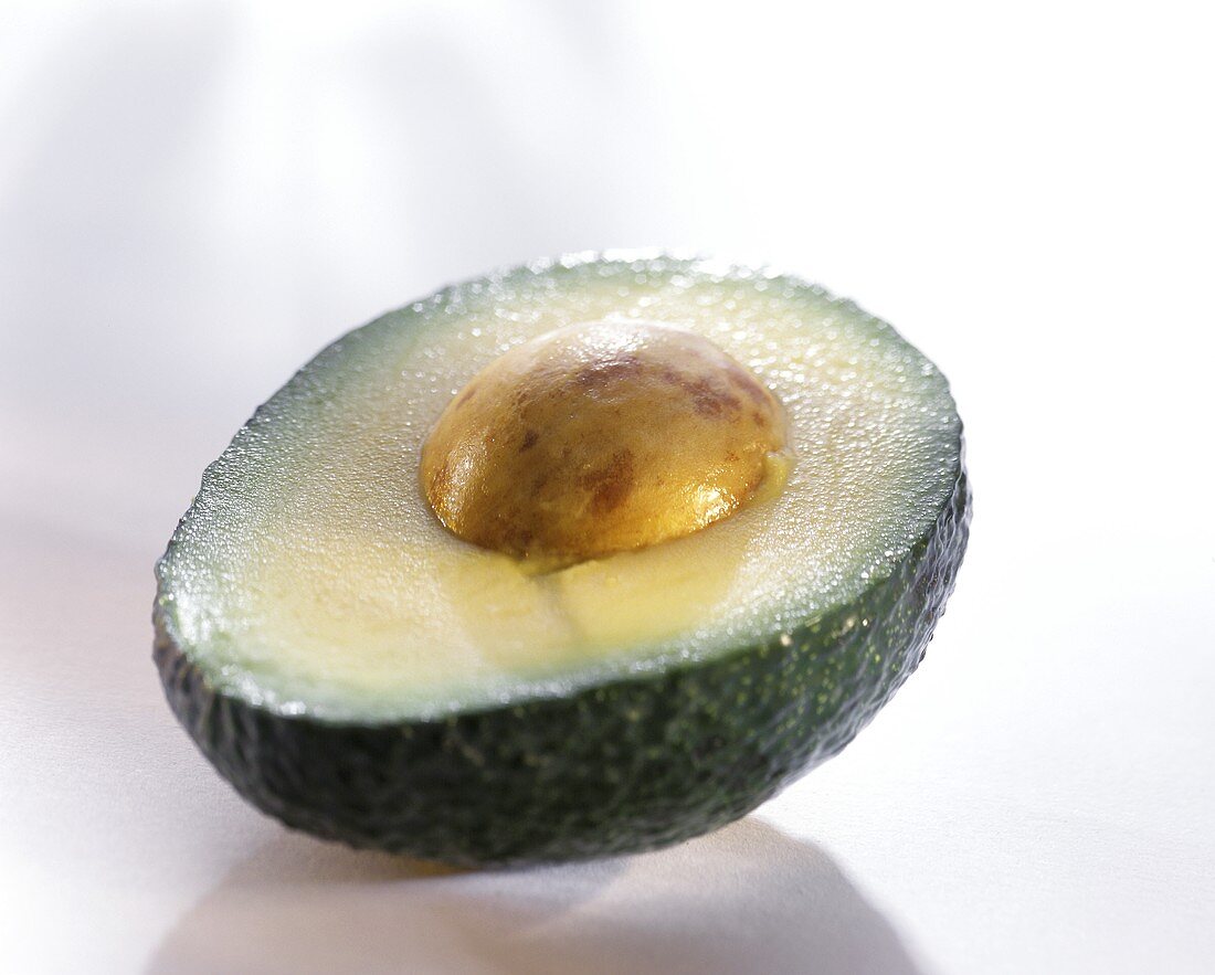 Avocado half with stone on a light background
