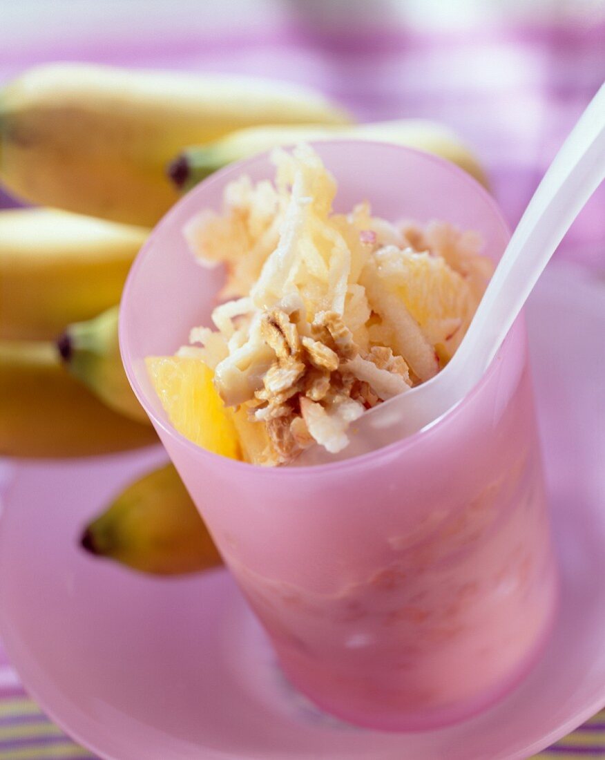 Muesli with bananas and oranges in jar with spoon